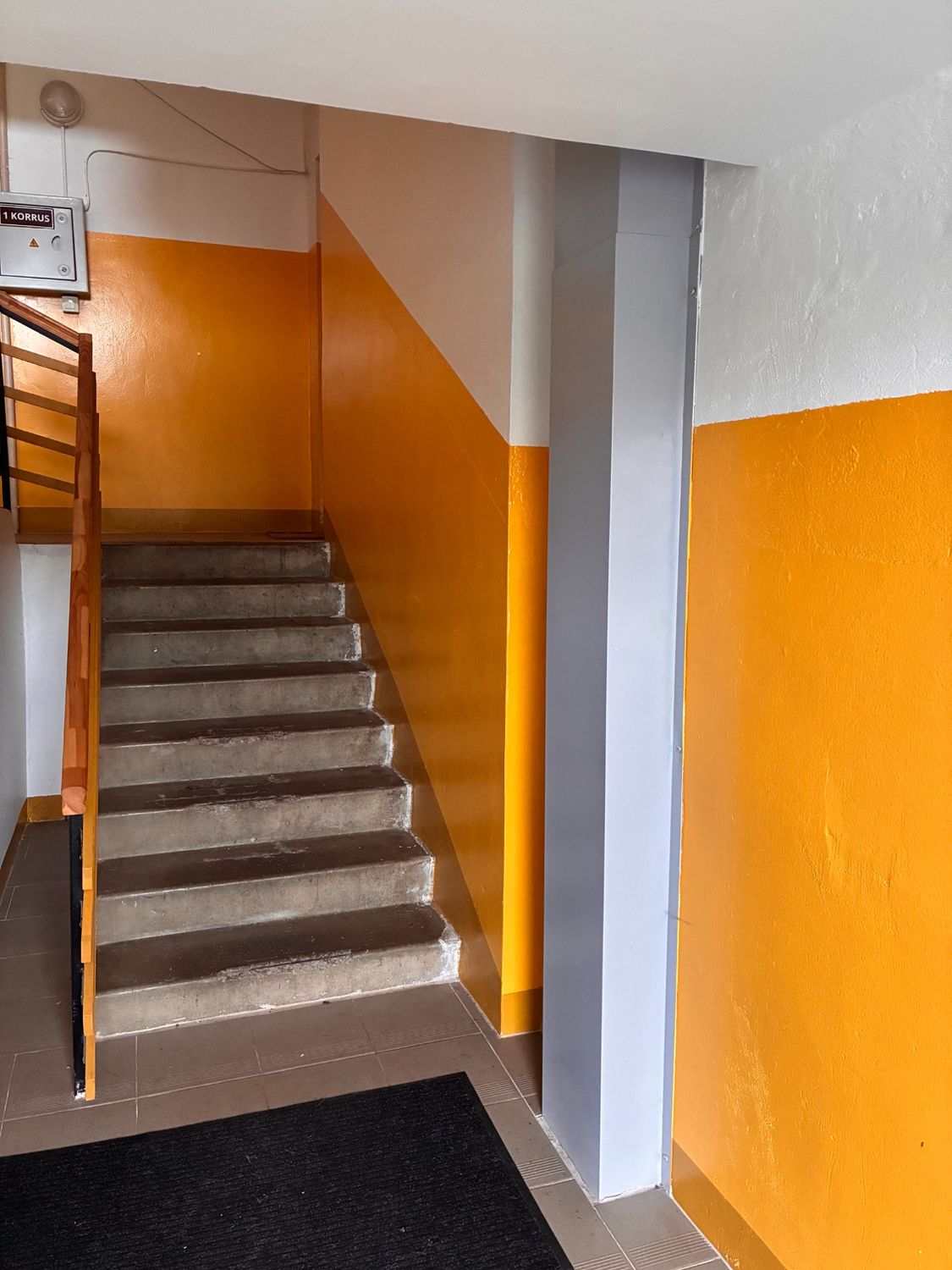 Orange stairwell with finished wall zones and grey details.