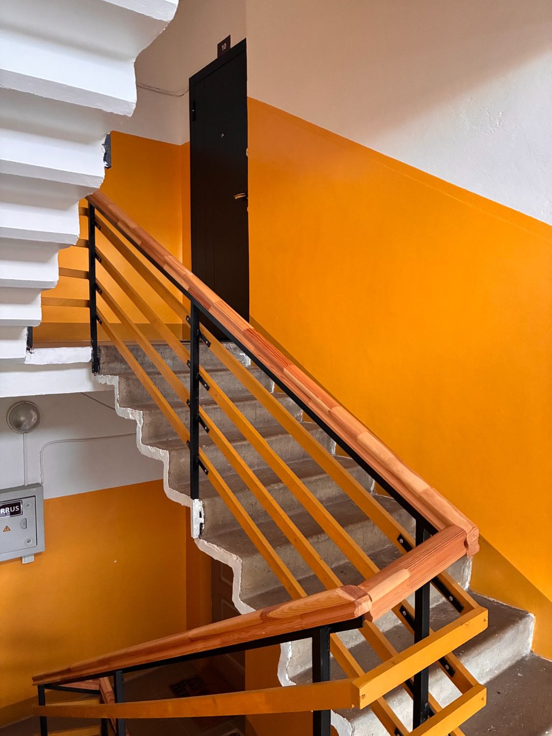 Orange stairwell with renewed handrails.
