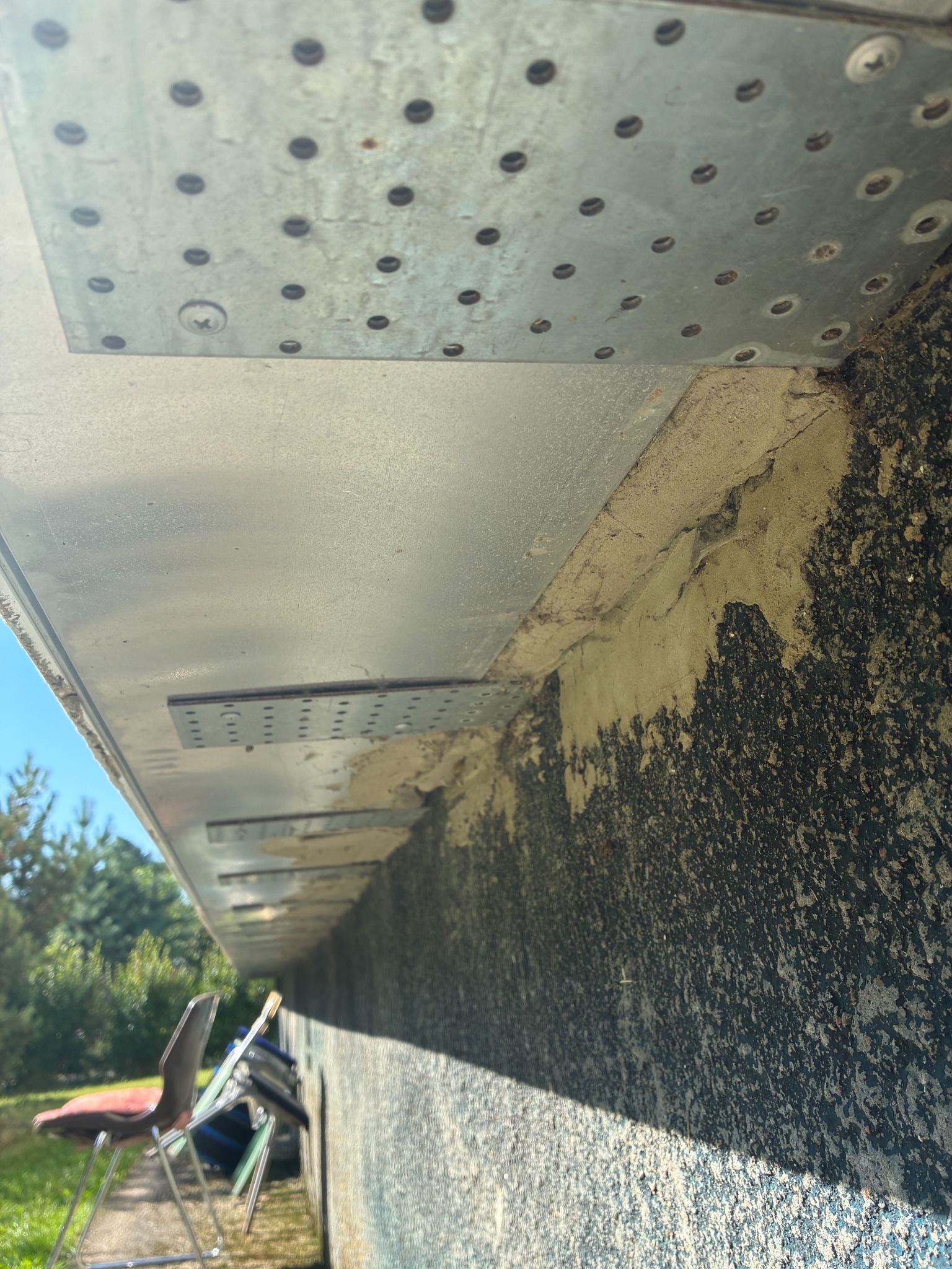 Continuous metal reinforcement and flashing line beneath the eaves
